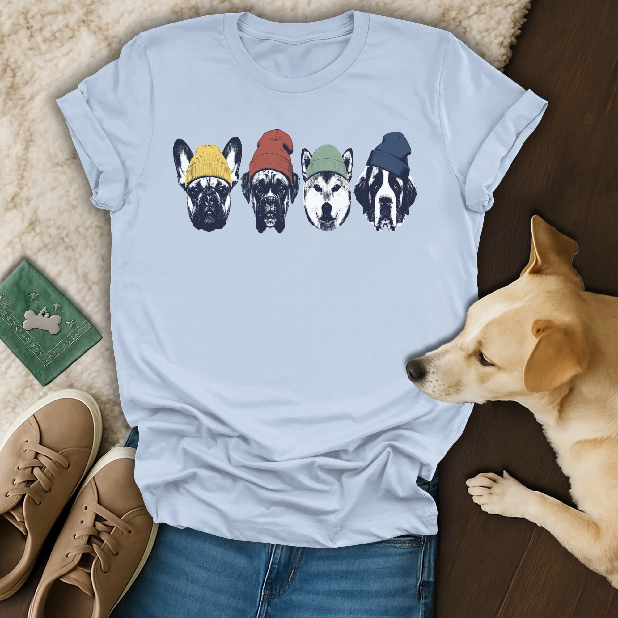Four dogs wearing colorful beanies are featured on a light blue t-shirt.