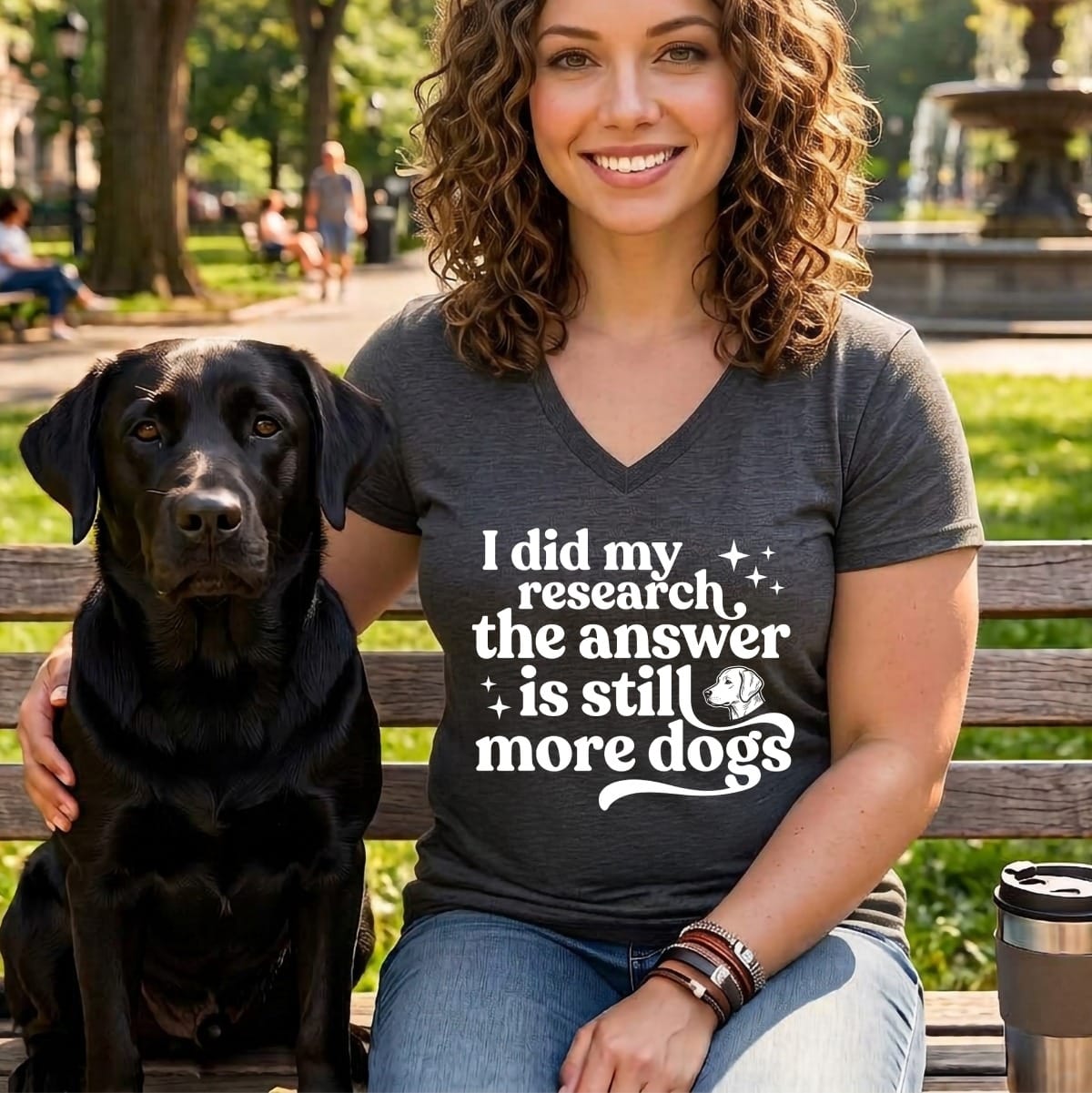 Woman and black Labrador sit on bench with "I did my research the answer is still more dogs" text.