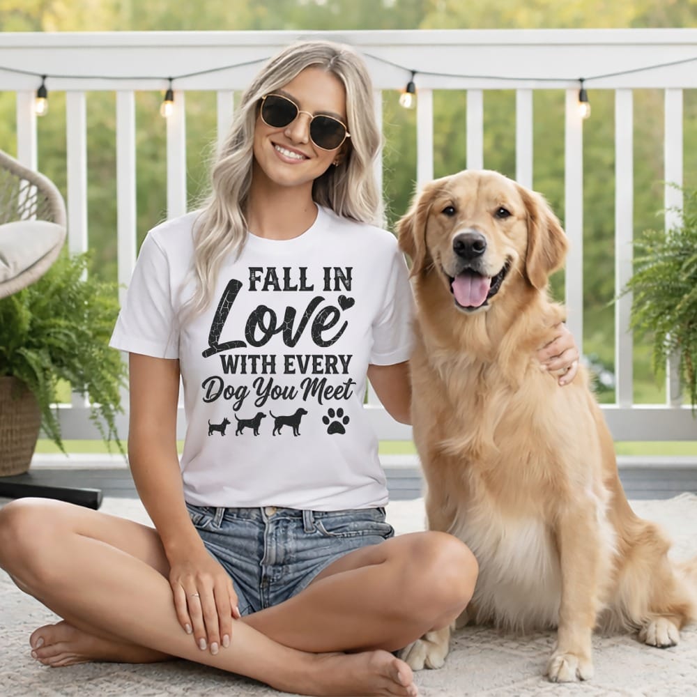 Woman in white t-shirt with "Fall in Love with Every Dog You Meet" text and dog graphics, sitting with a golden retriever.