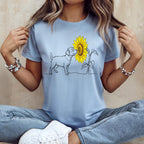 Light blue t-shirt with a minimalist line drawing of a dog looking at a sunflower.