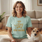 Woman wearing a mint green t-shirt with a golden retriever and rider graphic and "STAY GOLDEN" text.