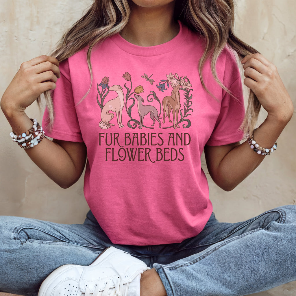 A person wearing a pink t-shirt featuring greyhound dogs, flowers, and the text Fur Babies and Flower Beds.