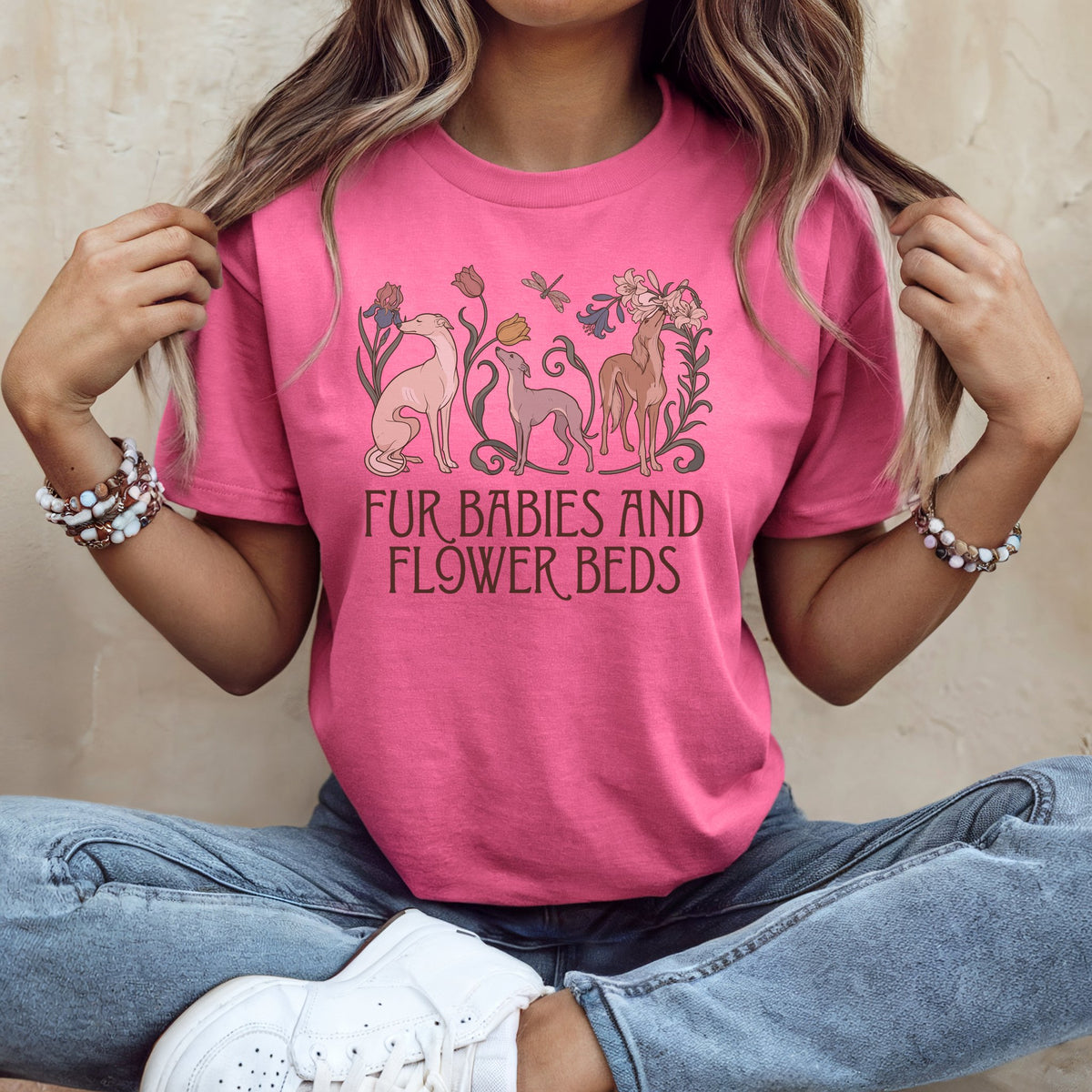 A person wearing a pink t-shirt featuring greyhound dogs, flowers, and the text Fur Babies and Flower Beds.