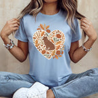 Light blue t-shirt with a heart graphic of a dog, leaves, mushrooms, and acorns.
