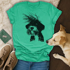Green t-shirt with a black doodle dog graphic and a dog lying next to it.