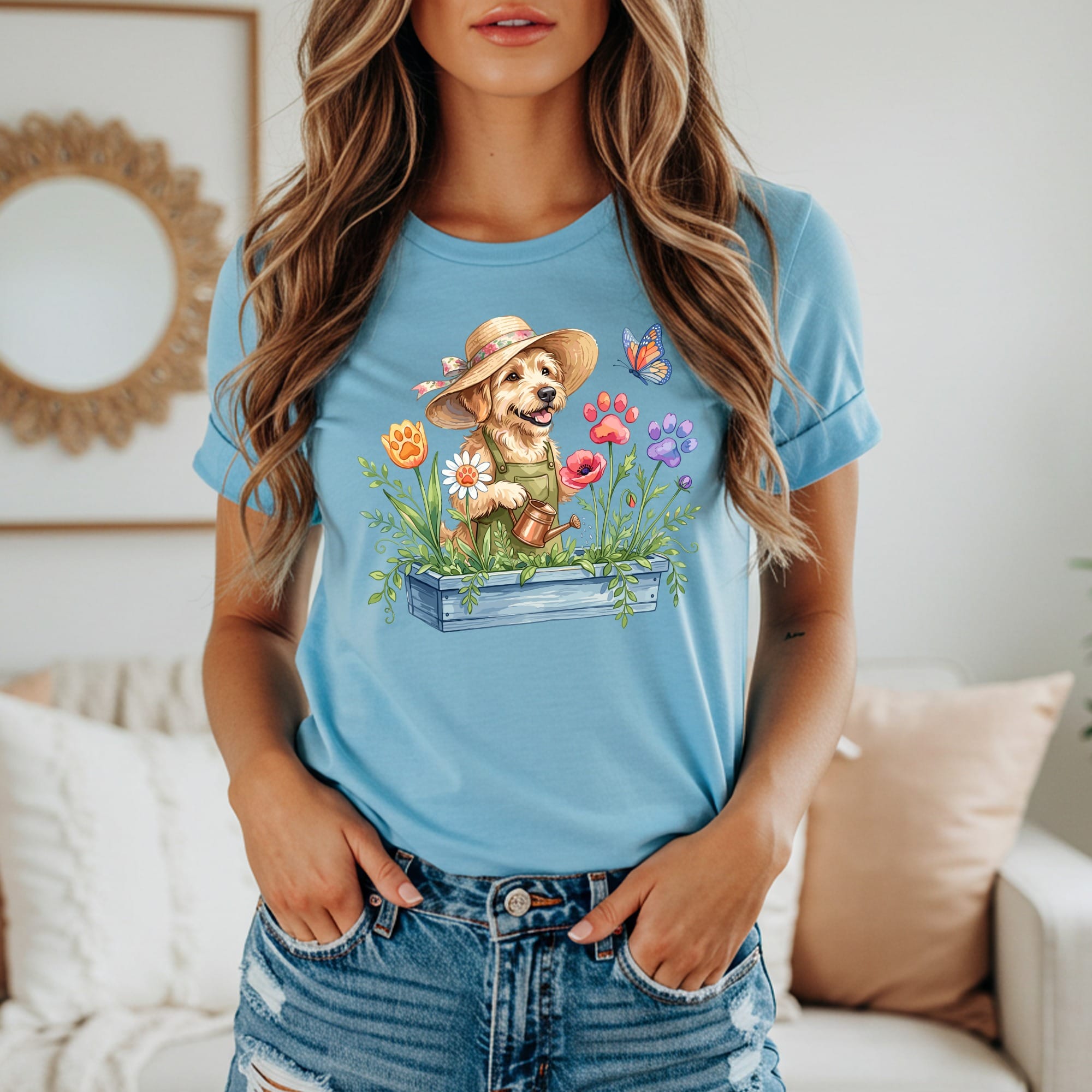 Light blue t-shirt with a watercolor print of a dog in a garden watering flowers.