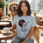 Woman with golden retriever at table, wearing t-shirt with vinyl record and dog playing guitar logo.