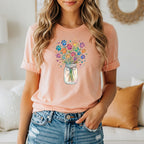 Peach t-shirt with a colorful paw print bouquet in a jar graphic.