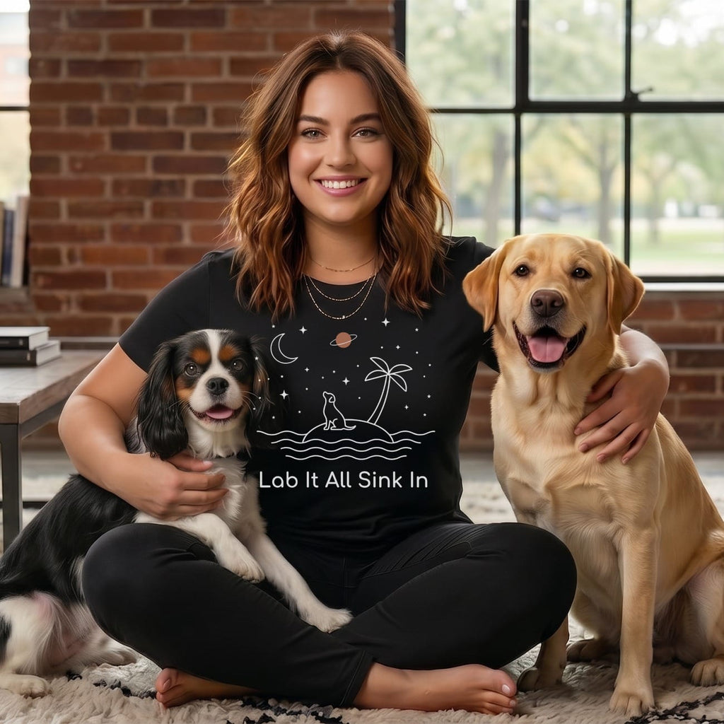 Woman with a dog and a Labrador retriever wearing a t-shirt with text.