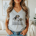 Tricolor dog with "Currently Between Projects" text on gray t-shirt.
