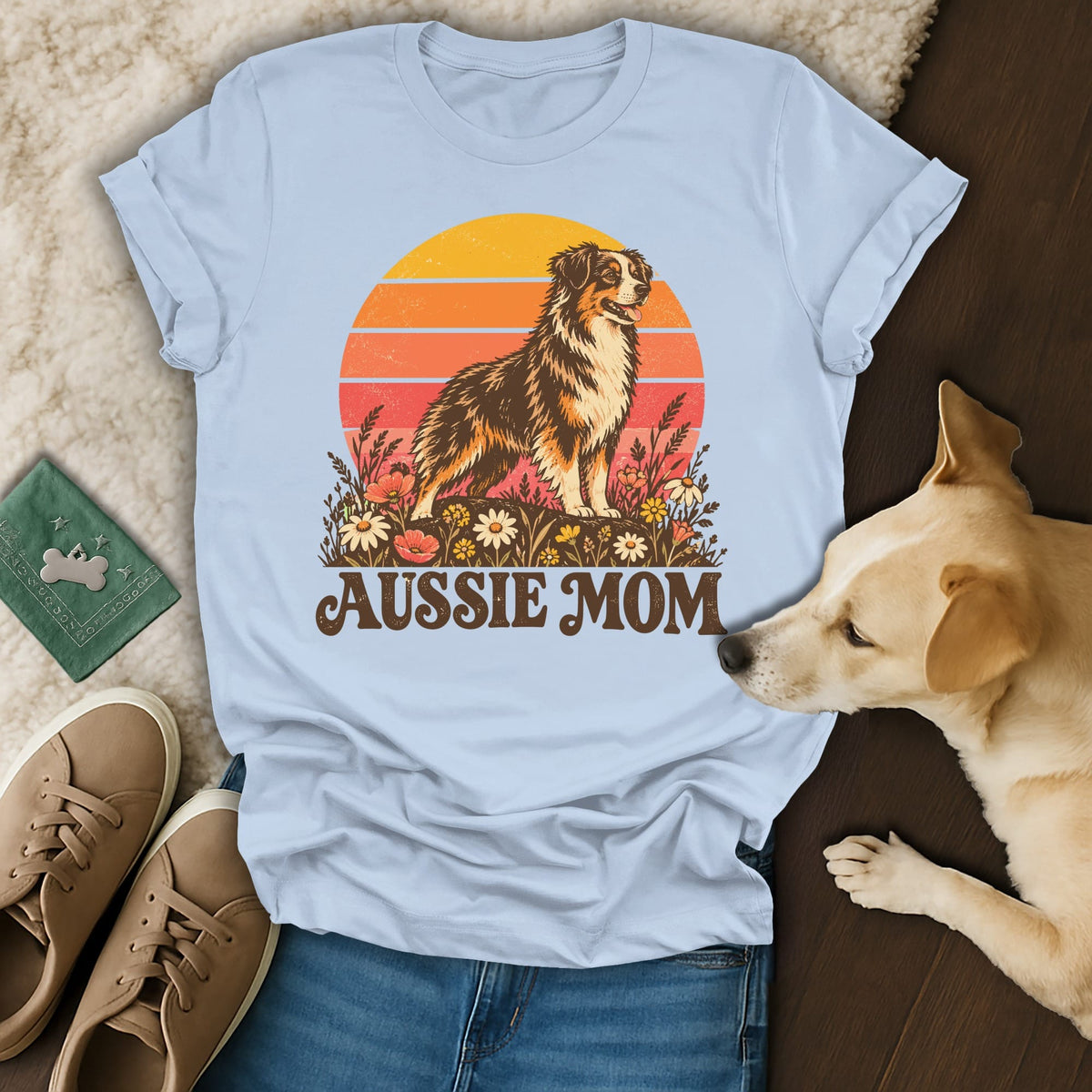 Light blue t-shirt featuring an Aussie Mom graphic with an Australian Shepherd dog, sunset, and flowers.