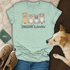 Light blue t-shirt with four dogs playing pickleball, text "SMASHIN' & dashin'".