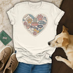 Cream t-shirt with embroidered heart of dog toys, paws, and bones.