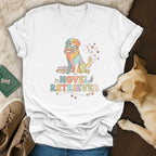Graphic tee with colorful dog holding books and text "Novel Retriever".