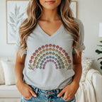 A woman wearing a grey V-neck t-shirt featuring a colorful rainbow made of paw prints.