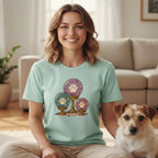 A smiling woman wears a mint green t-shirt with a crystal ball and paw print graphic, sitting next to a Jack Russell Terrier.
