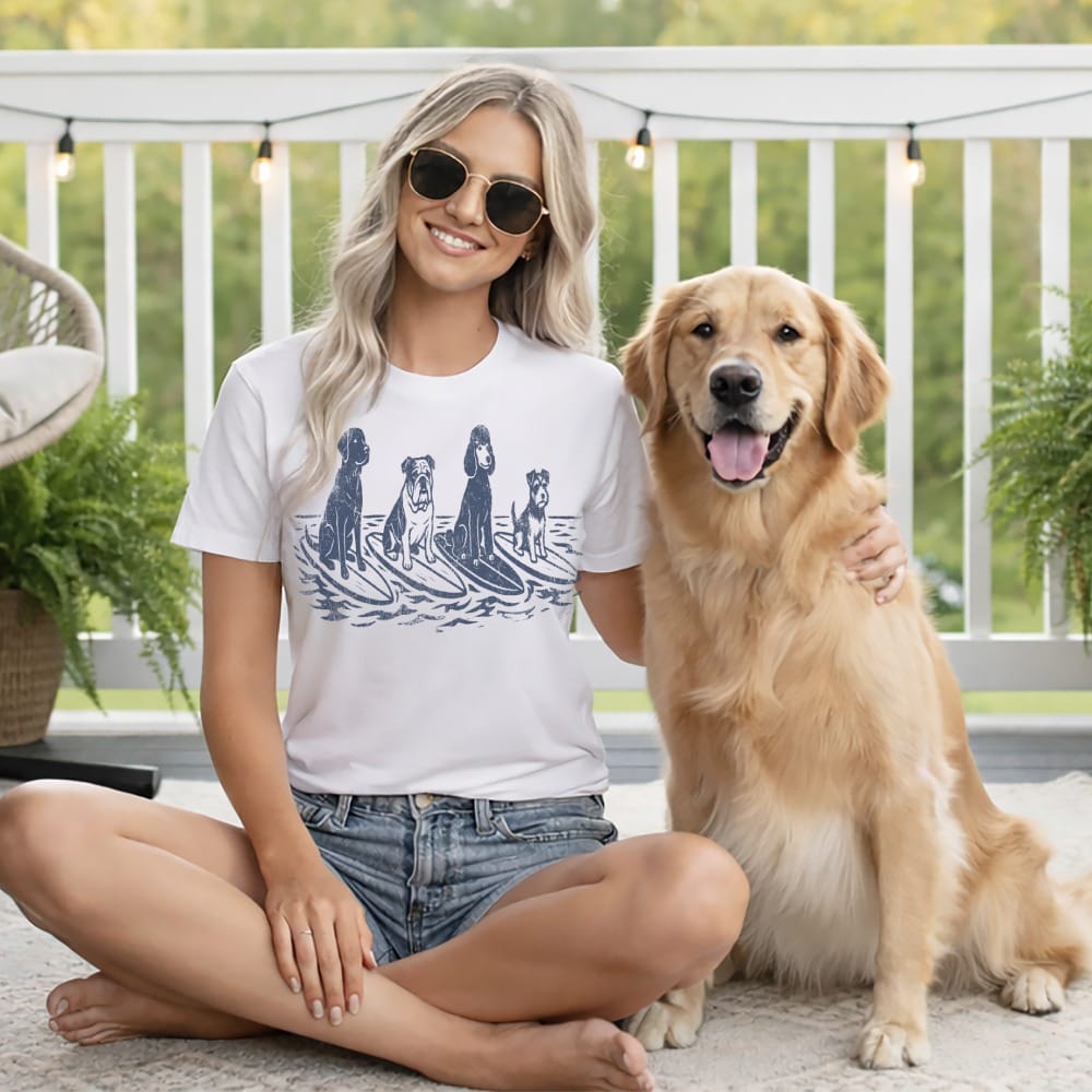 Woman in t-shirt with dogs on surfboards, sitting with golden retriever.