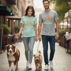 Couple walking two dogs on a street, both wearing t-shirts with dog graphics.