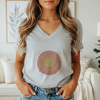 A woman wearing a gray V-neck t-shirt featuring a graphic of a vinyl record with the text Love on Repeat.
