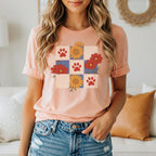 Peach t-shirt with floral and paw print checkerboard graphic.