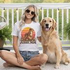 A blonde woman wearing sunglasses and a white Aussie Mom t-shirt sits with a golden retriever outdoors.