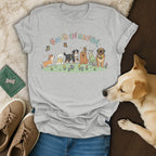 Grey t-shirt with "Paws In Bloom" text and cartoon dogs in a garden.