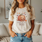 Dog peeking from pumpkin with text "Cutest in the Patch" and falling leaves.