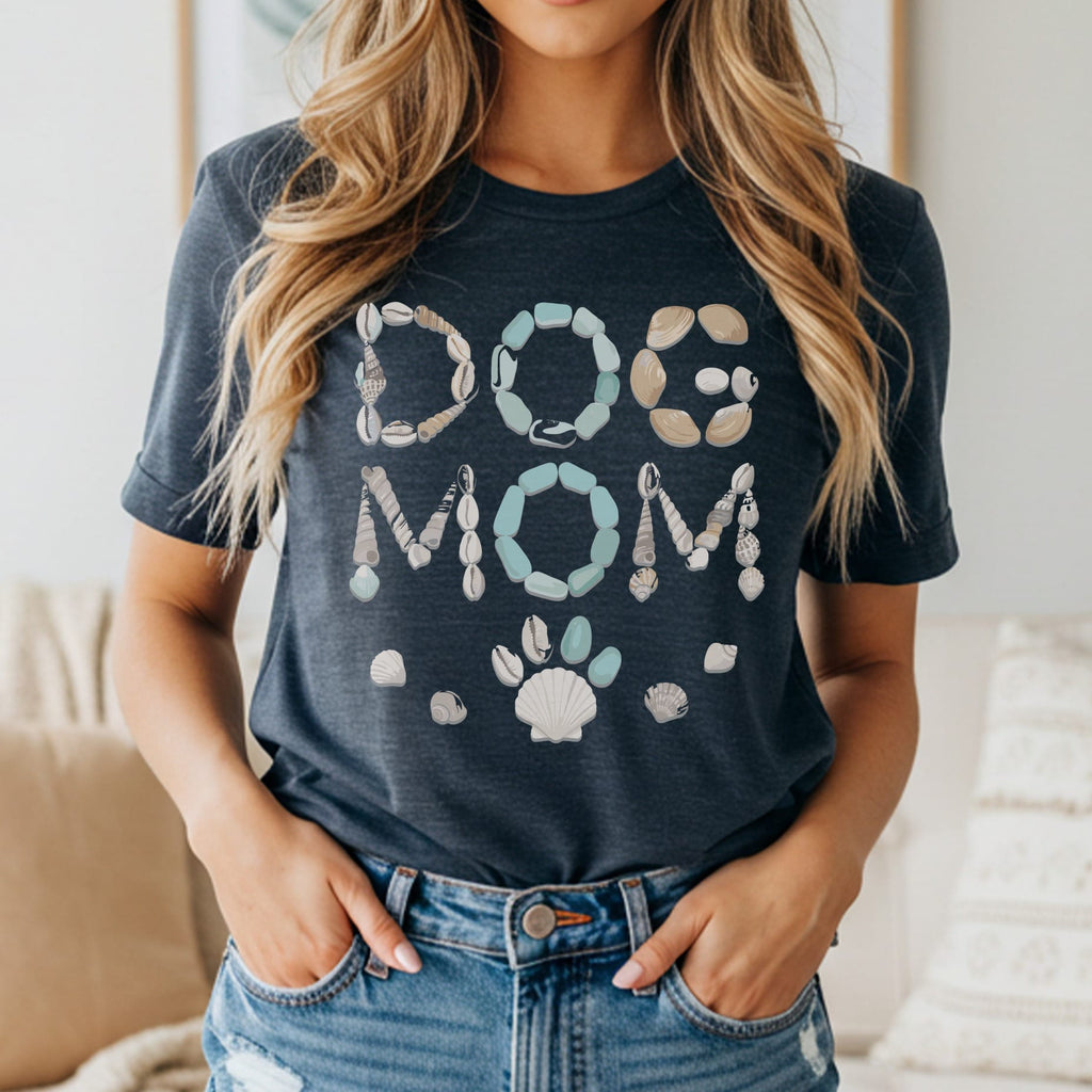 "Dog Mom" text made of seashells and stones, with a paw print and shells below.