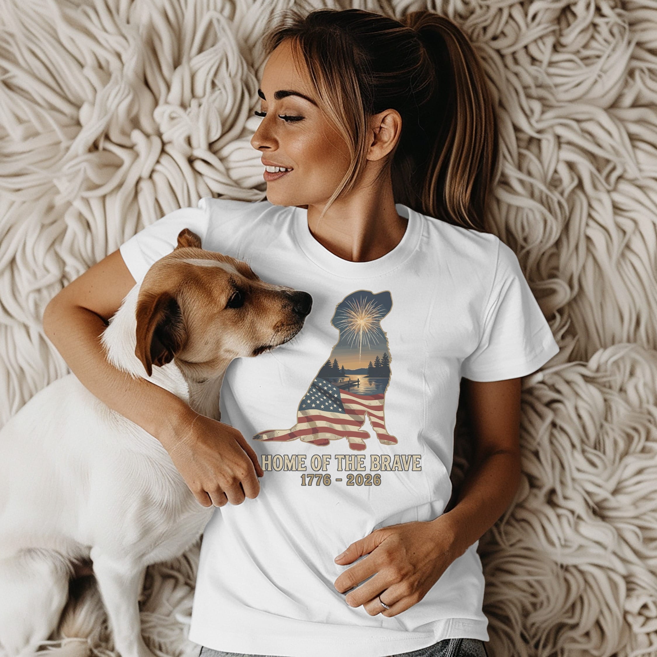 Woman with dog wears white t-shirt with patriotic sunset graphic.
