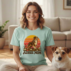 A smiling woman wearing a light blue t-shirt that says "AUSSIE MOM" with a dog graphic.