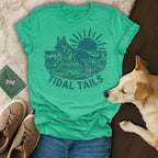 Green t-shirt with a German Shepherd surfing on a wave, text "TIDAL TAILS".