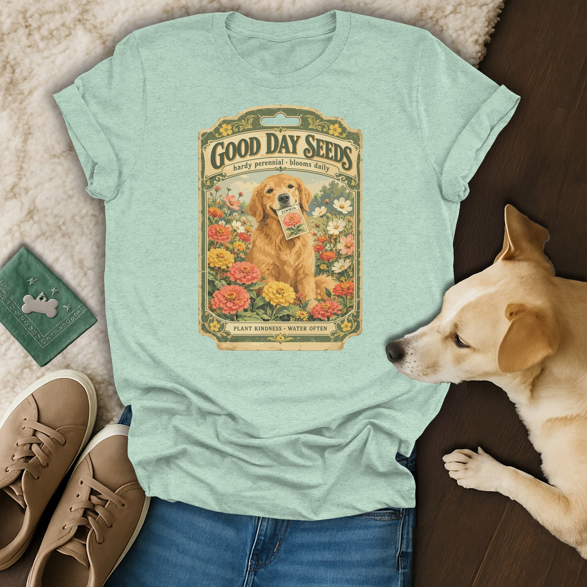A mint green t-shirt featuring a vintage seed packet graphic with a golden retriever holding a zinnia packet.