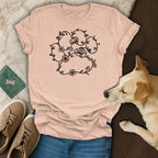 Peach t-shirt with a floral paw print design, next to a dog.