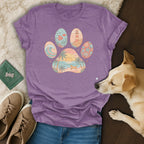Purple t-shirt with paw print graphic featuring beach, ocean, and lighthouse scenes.
