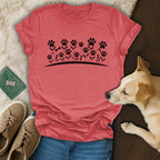 Red t-shirt with a floral paw print and bone design, beside a dog and shoes.