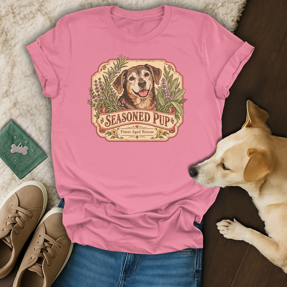 A pink crewneck t-shirt featuring a graphic of a dog surrounded by herbs and the text Seasoned Pup.