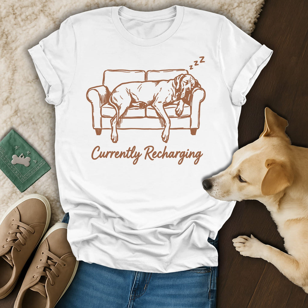 White t-shirt with graphic of a dog sleeping on a couch and text "Currently Recharging".