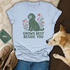 A light blue t-shirt with a graphic of a dog and flowers reads GROWS BEST BESIDE YOU.