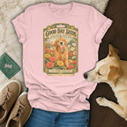 Pink t-shirt featuring a vintage seed packet graphic with a golden retriever surrounded by flowers, laid out with jeans, shoes, and a real dog.