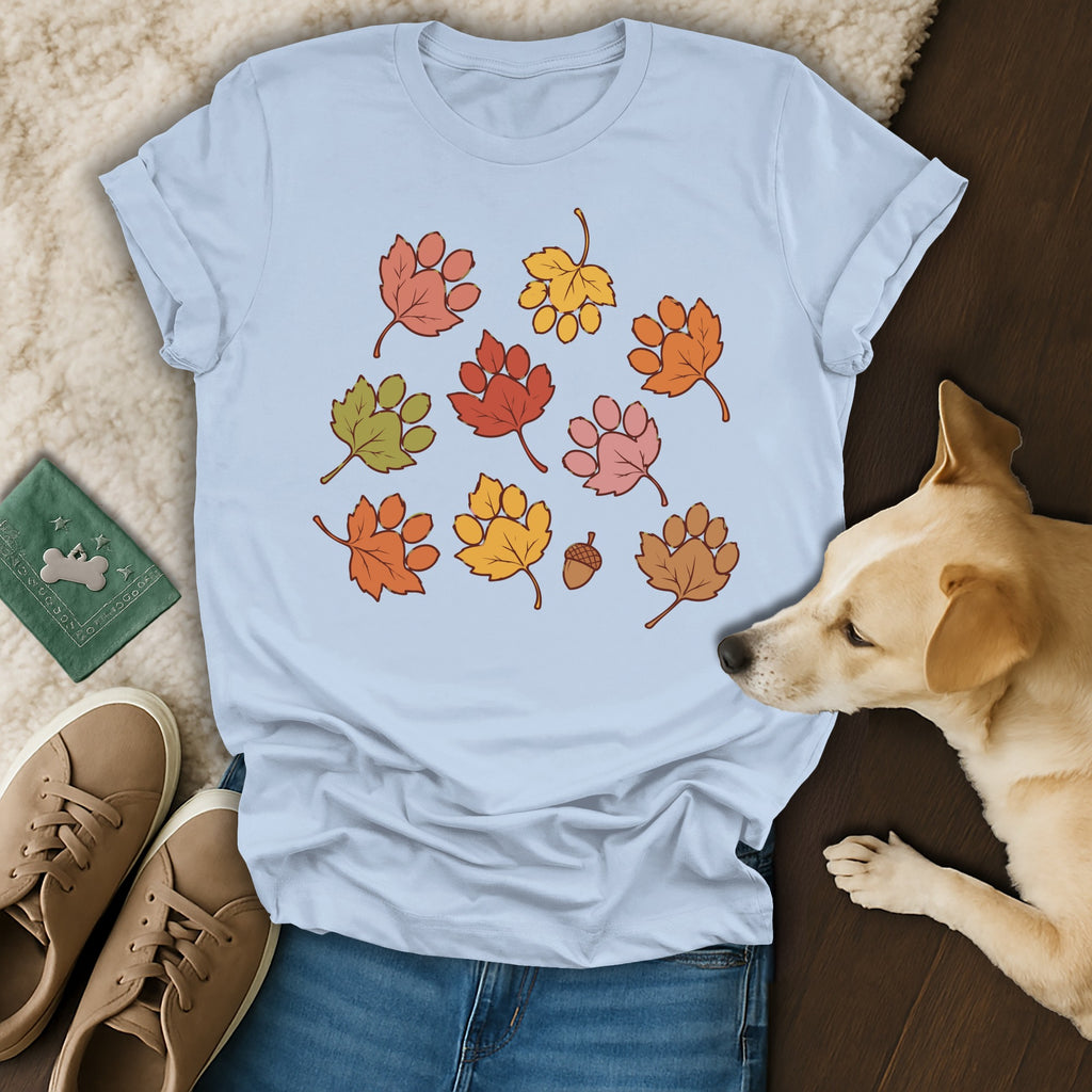 Light blue crewneck t-shirt featuring fall leaves shaped like paw prints, displayed with jeans, sneakers, and a dog.