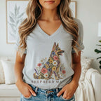 A woman wears a grey V-neck t-shirt featuring a floral German Shepherd and the text Shepherd Mama.