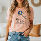 Peach t-shirt with a black line drawing of a dog flying a yellow and blue kite.