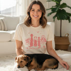 Woman wearing cream t-shirt with stylized dogs and waves graphic.