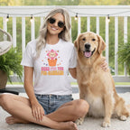 Woman with golden retriever wearing a white t-shirt with dog and flower graphic and text.