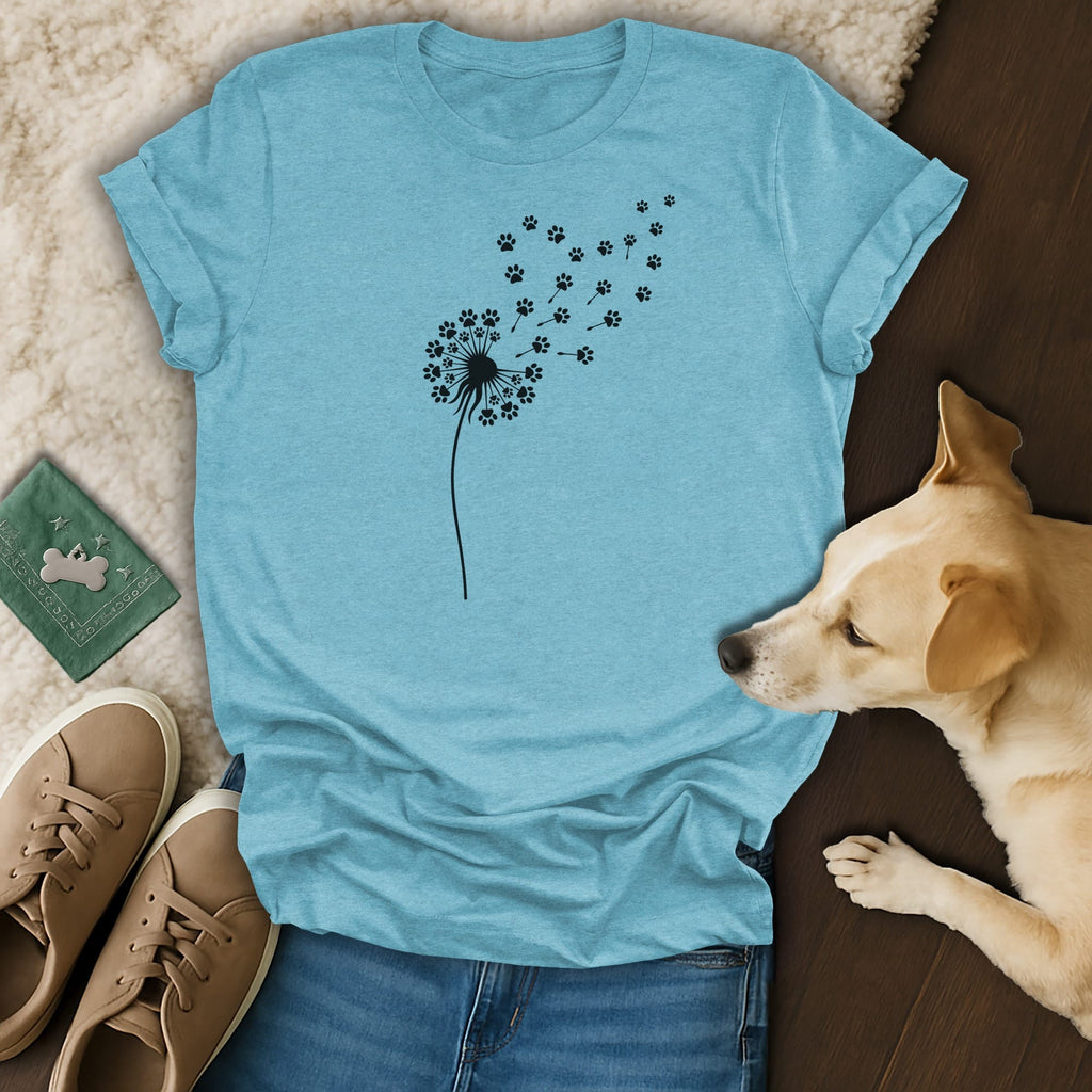 Teal t-shirt with black dandelion and paw print design, next to dog and shoes.