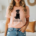 Woman wearing peach t-shirt with black dog graphic and text.
