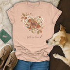 Peach t-shirt with a heart design of autumn florals, foliage, and a dog silhouette.