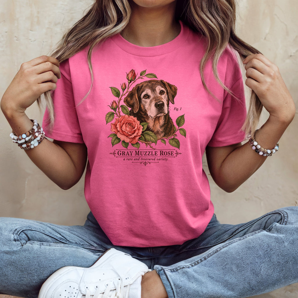 A person wearing a pink t-shirt with a vintage graphic of a dog and pink roses.