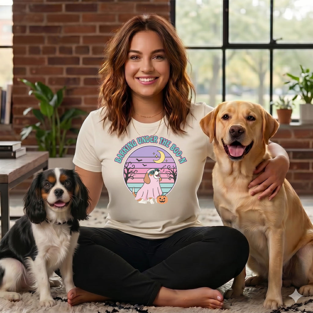 Woman with two dogs wearing a shirt with a Halloween dog graphic.