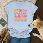 Light blue t-shirt with a cartoon dog, flowers, and text "Love Everybody Okay, mostly dogs."